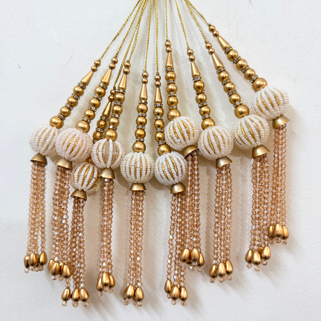 Decorative hanging beads with gold and beige colors on a white background