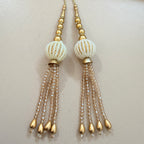Pair of beaded earrings with gold and white beads on a light background