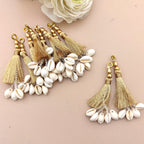 Decorative keychain with tassels and cowrie shells on a beige background
