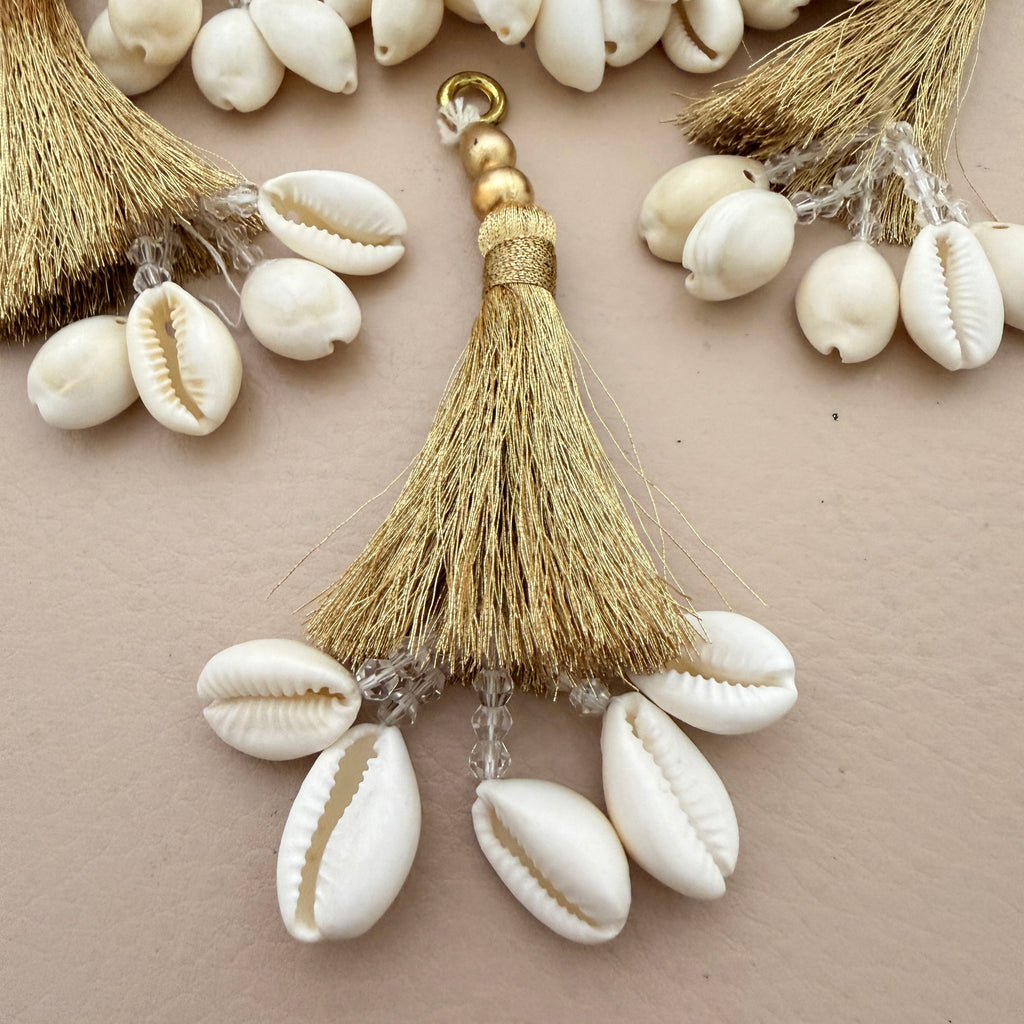 Decorative keychain with tassel and cowrie shells on a beige background