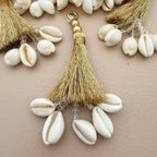 Decorative keychain with tassel and cowrie shells on a beige background