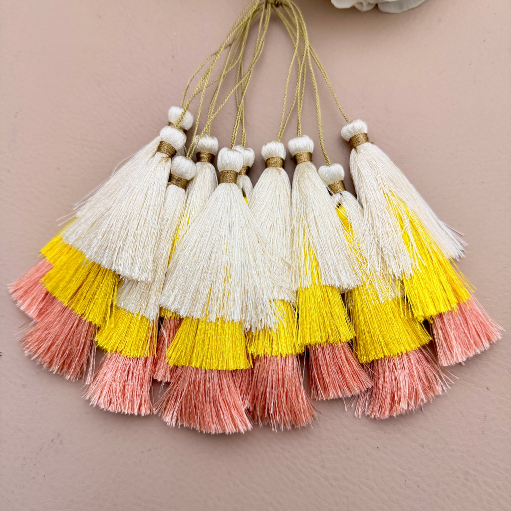 Set of tassels with yellow, pink, and white colors on a beige background