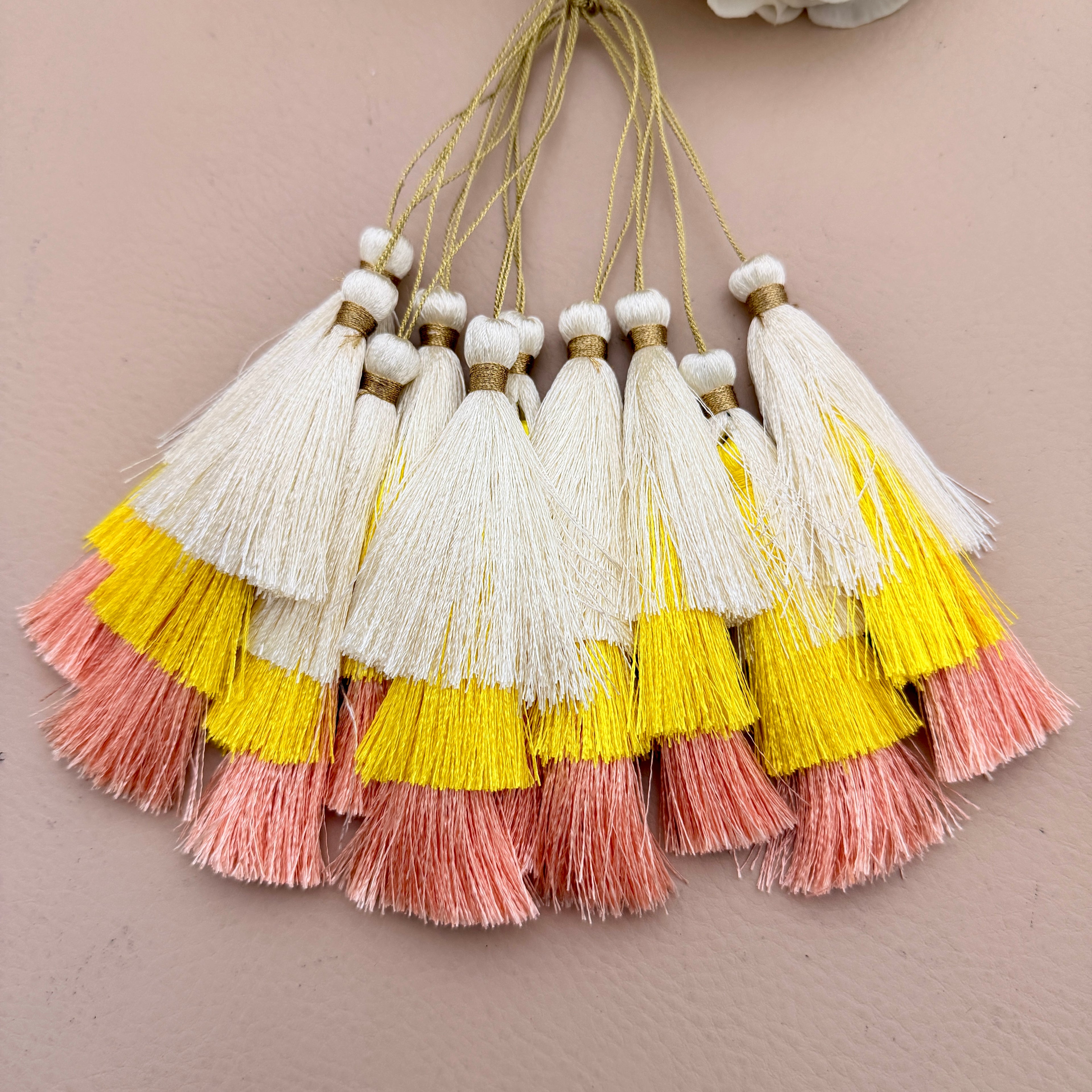 Set of tassels with yellow, pink, and white colors on a beige background