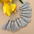 Silver tassels with beads on a beige background with yellow flowers