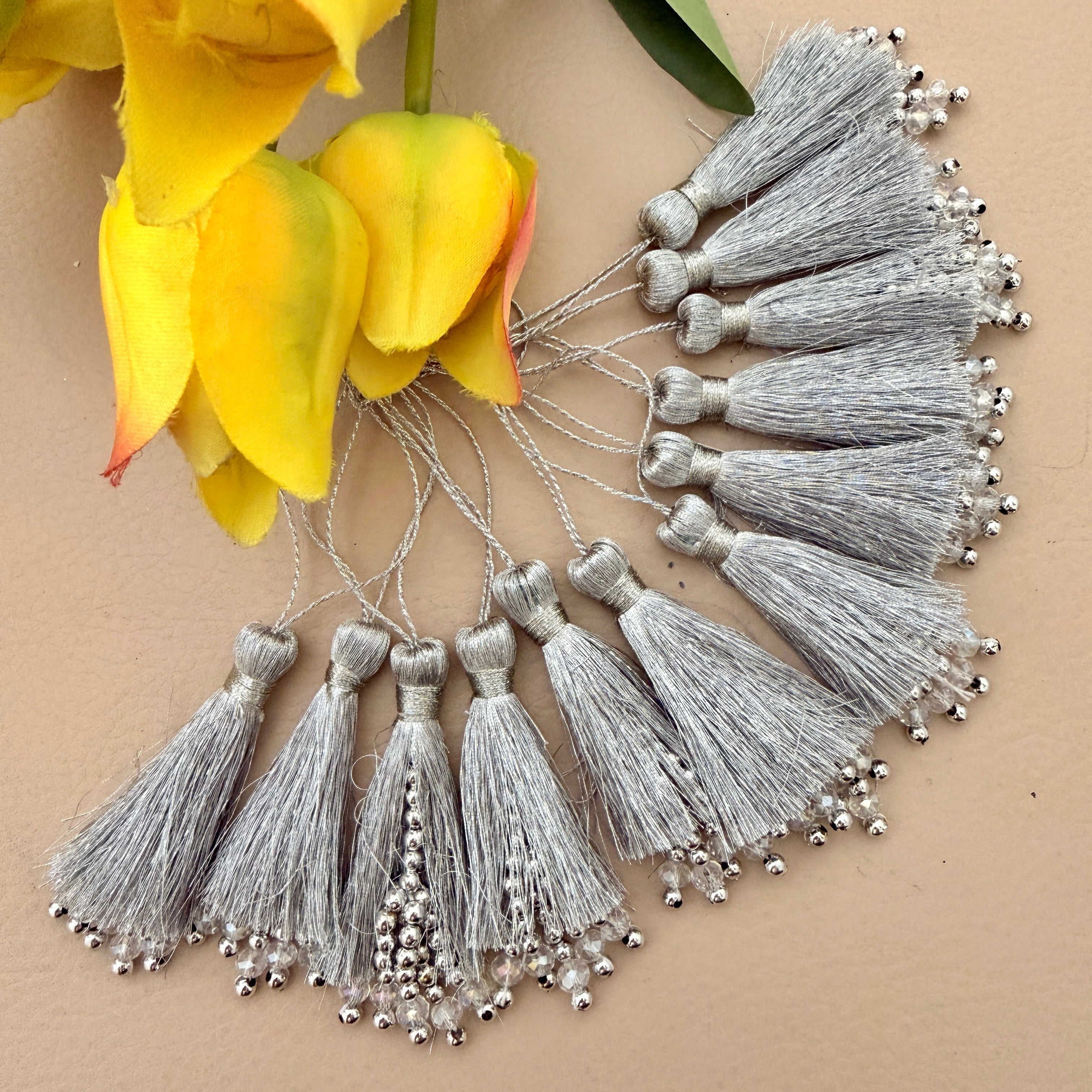 Silver tassels with beads on a beige background with yellow flowers