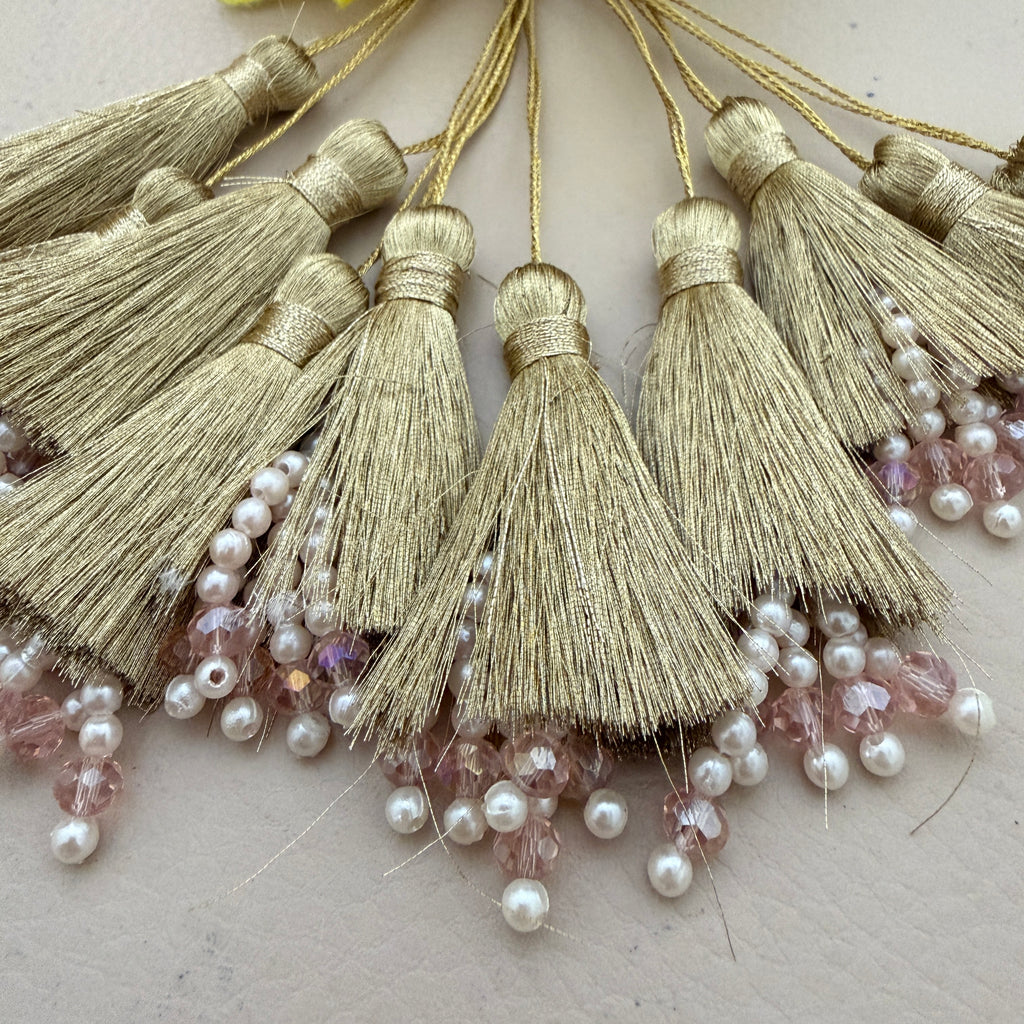Gold tassels with pearls and beads on a light background