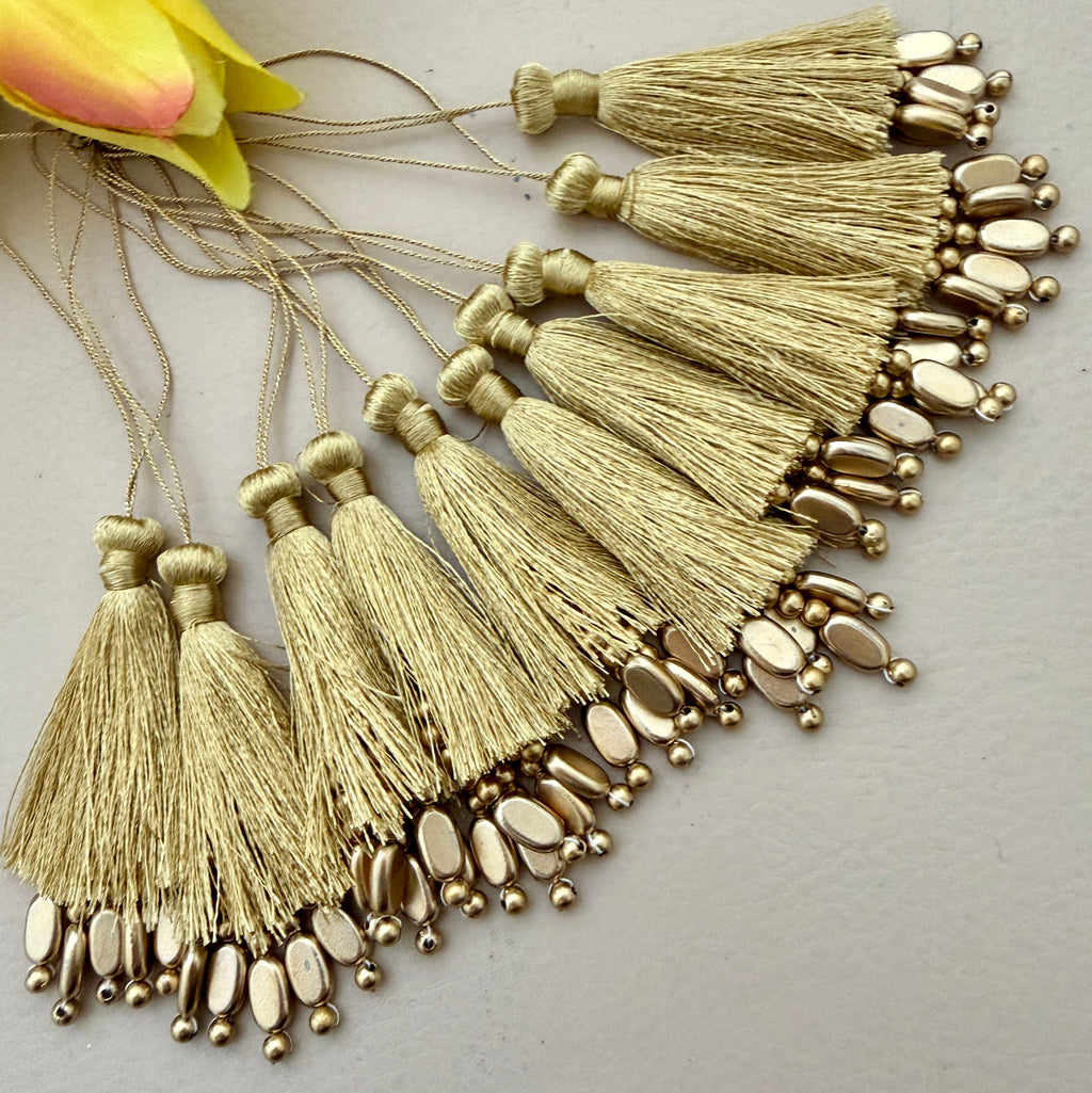 Gold tassels with beads on a light gray background