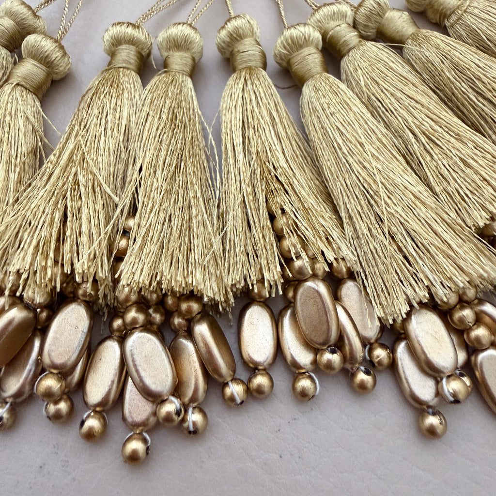 Close-up of gold tassels and beads on a white background