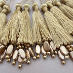 Close-up of gold tassels and beads on a white background