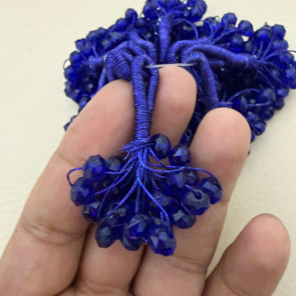 Blue beaded string held between fingers against a beige background