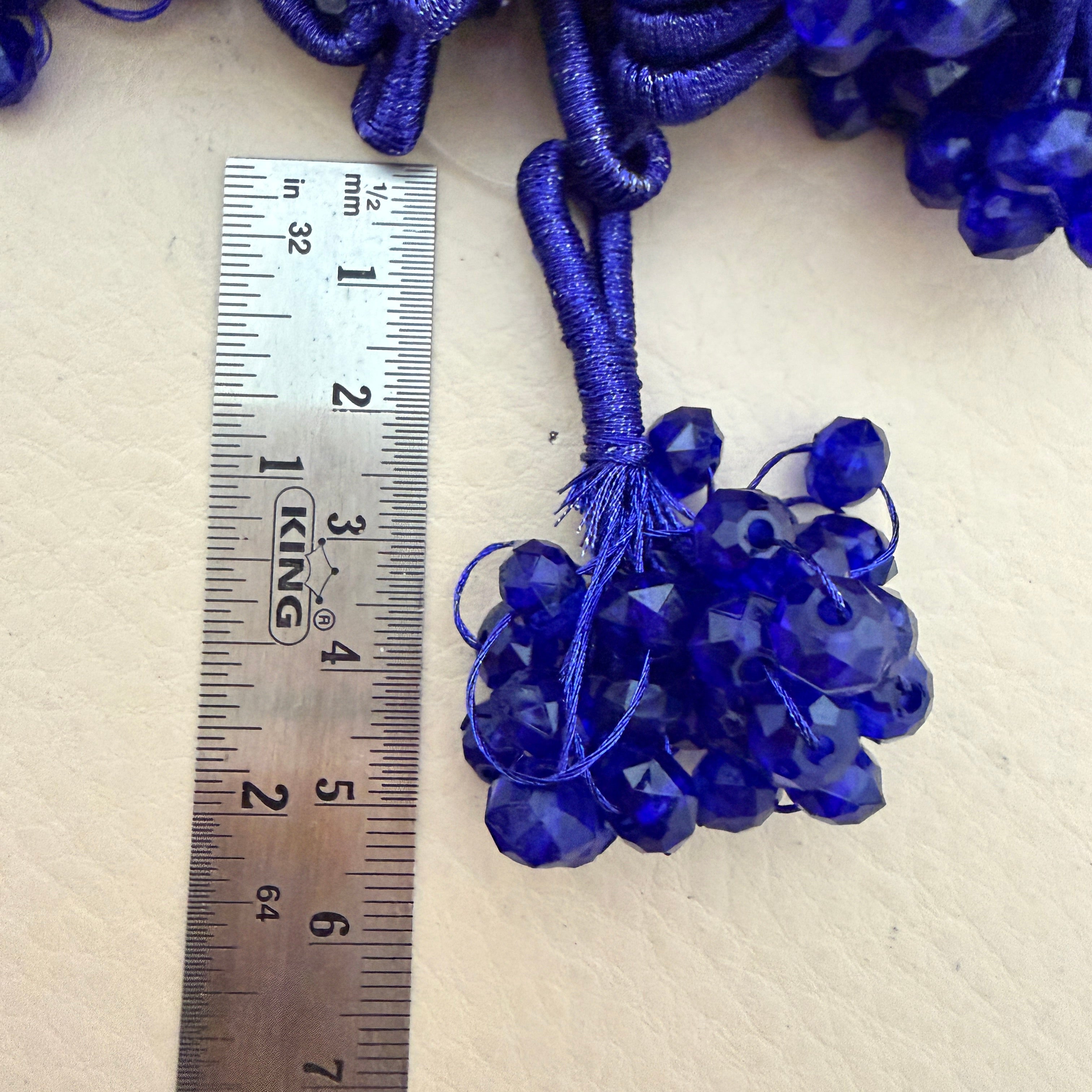 Blue beads with a ruler for scale on a beige background