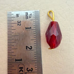 Red teardrop-shaped pendant with gold hook on a ruler for scale