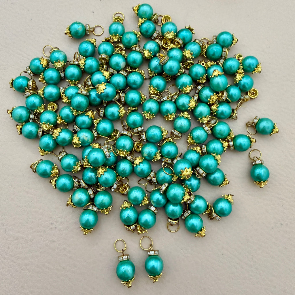 Turquoise pearl-like beads with gold accents on a light gray background