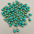 Turquoise pearl-like beads with gold accents on a light gray background
