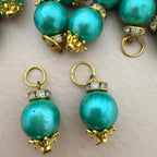 Turquoise pearl earrings with gold and diamond accents on a light background