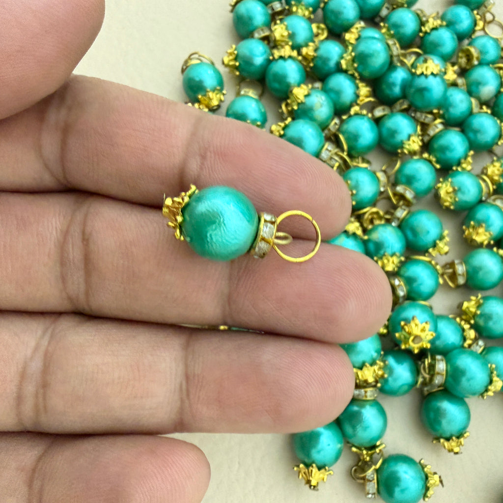 Turquoise pearl necklace with gold accents held by a hand