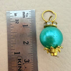Turquoise pendant with gold accents next to a ruler on a beige background