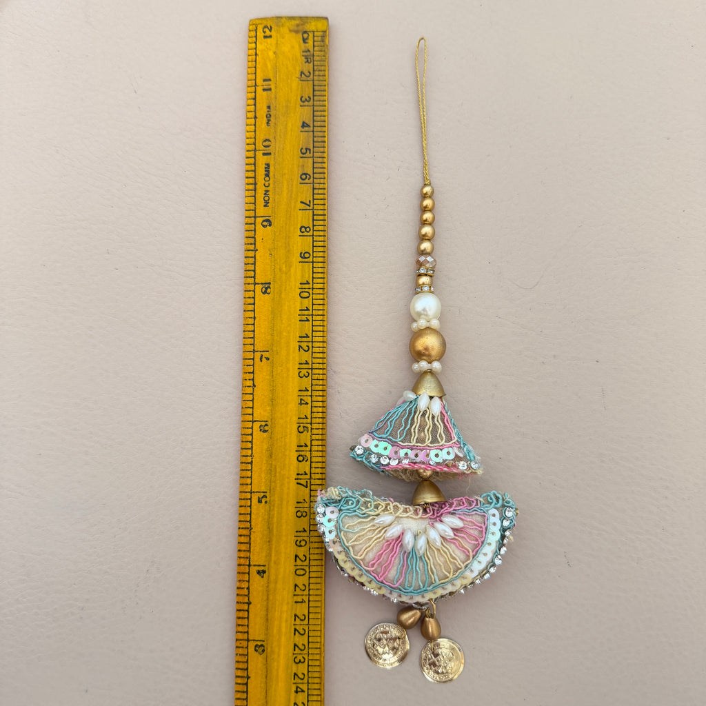 Decorative hanging ornament next to a ruler on a beige background