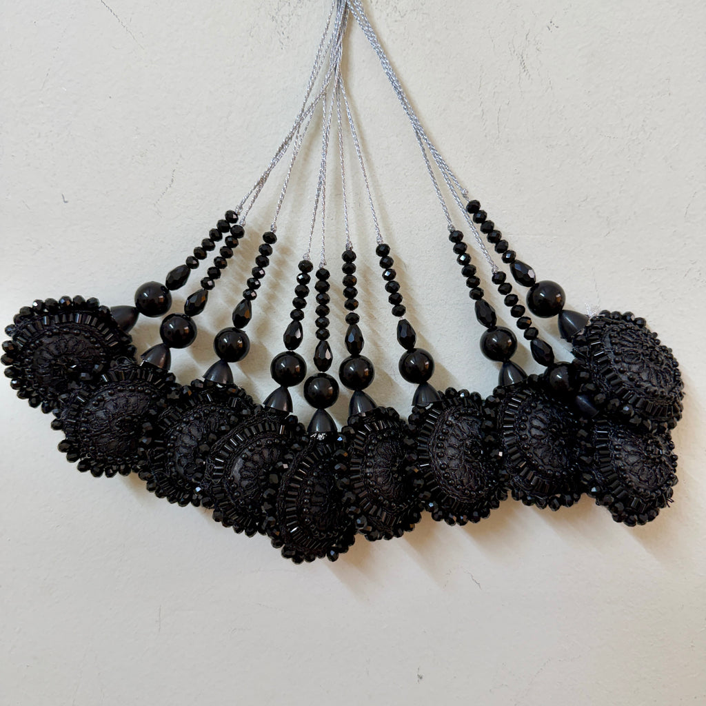 Black beaded necklaces on a light gray background