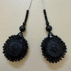 Pair of black beaded earrings on a beige background