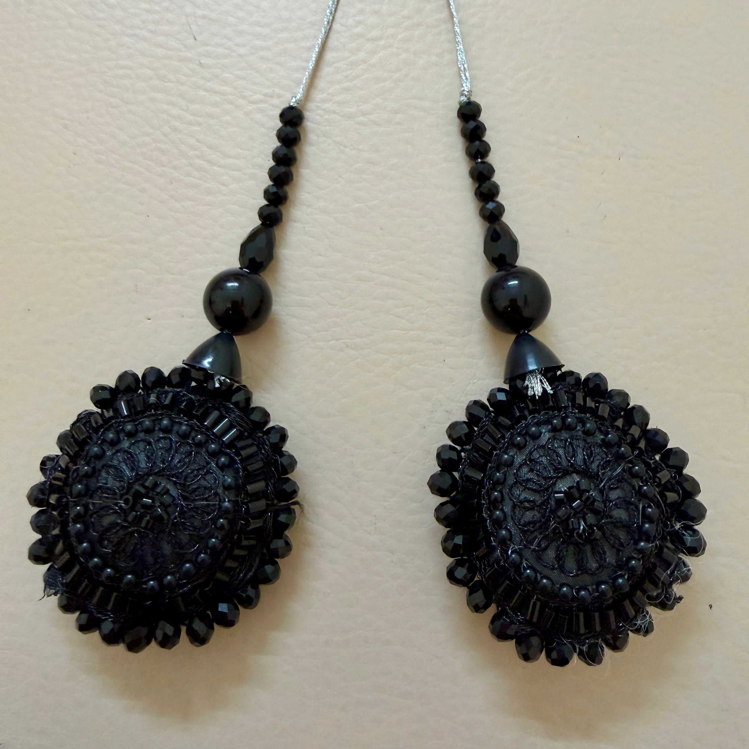 Pair of black beaded earrings on a beige background