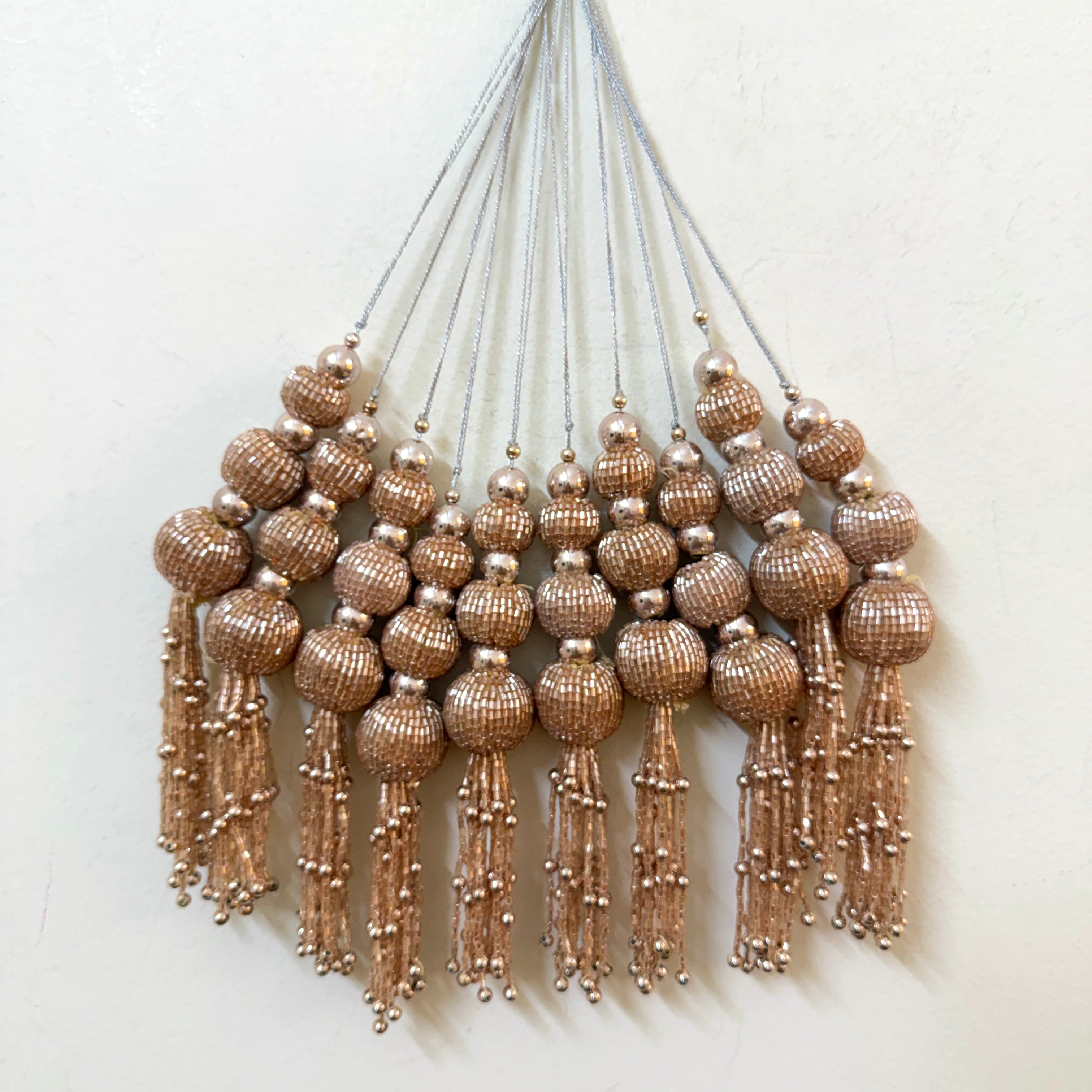 Decorative wall hanging with beaded tassels on a white background