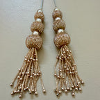 Pair of gold beaded tassel earrings on a light gray background