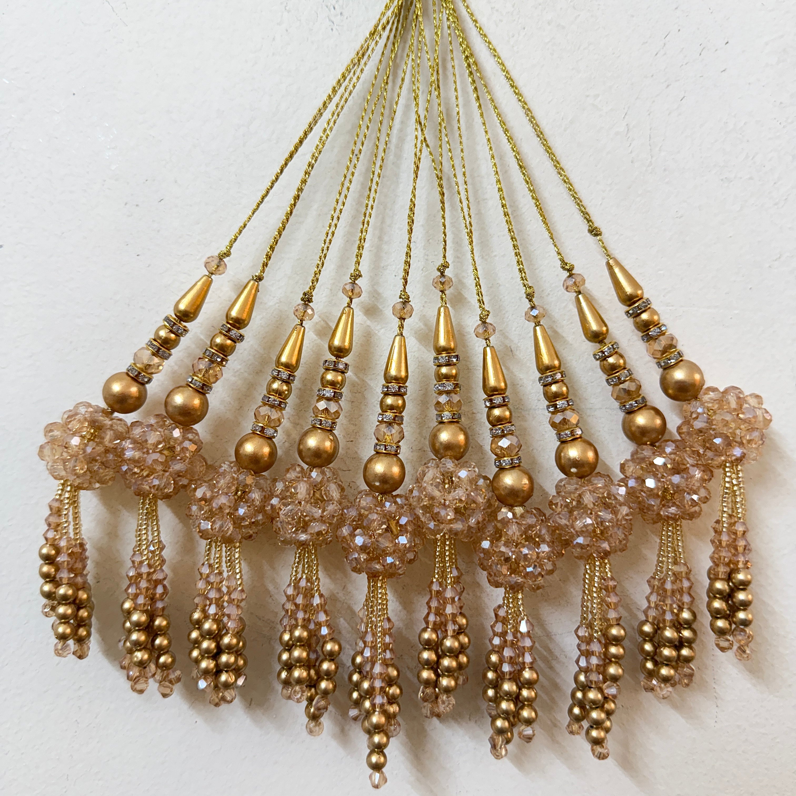 Set of gold and beige beaded tassels on a textured white background