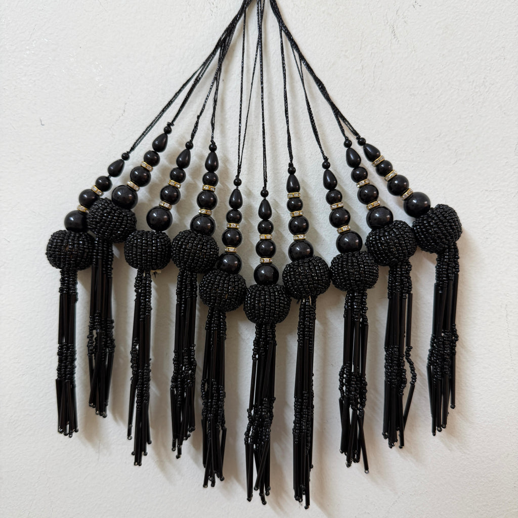 Black beaded tassel necklace on a light background