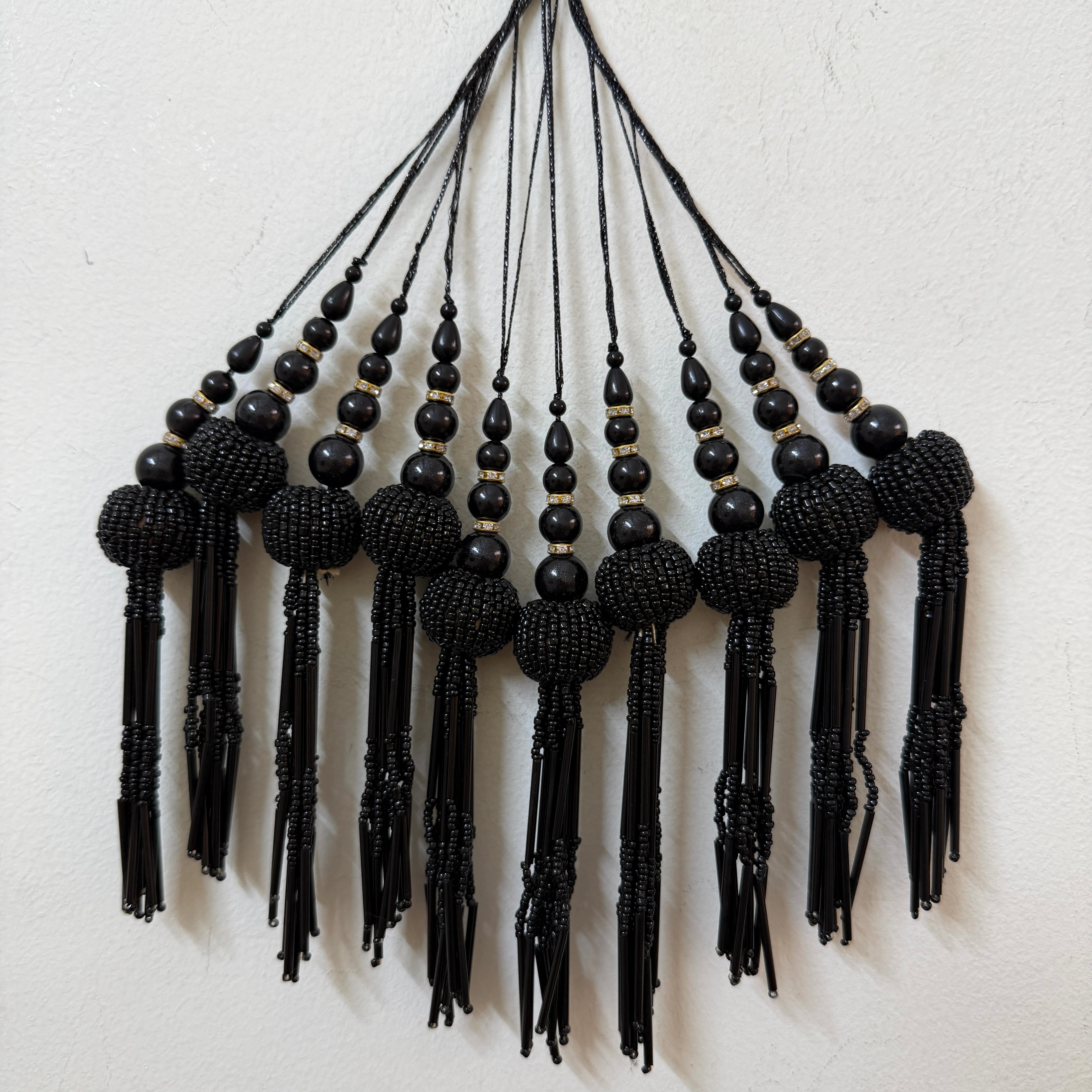 Black beaded tassel necklace on a light background