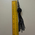 Black beaded tassel with a ruler for scale on a white background