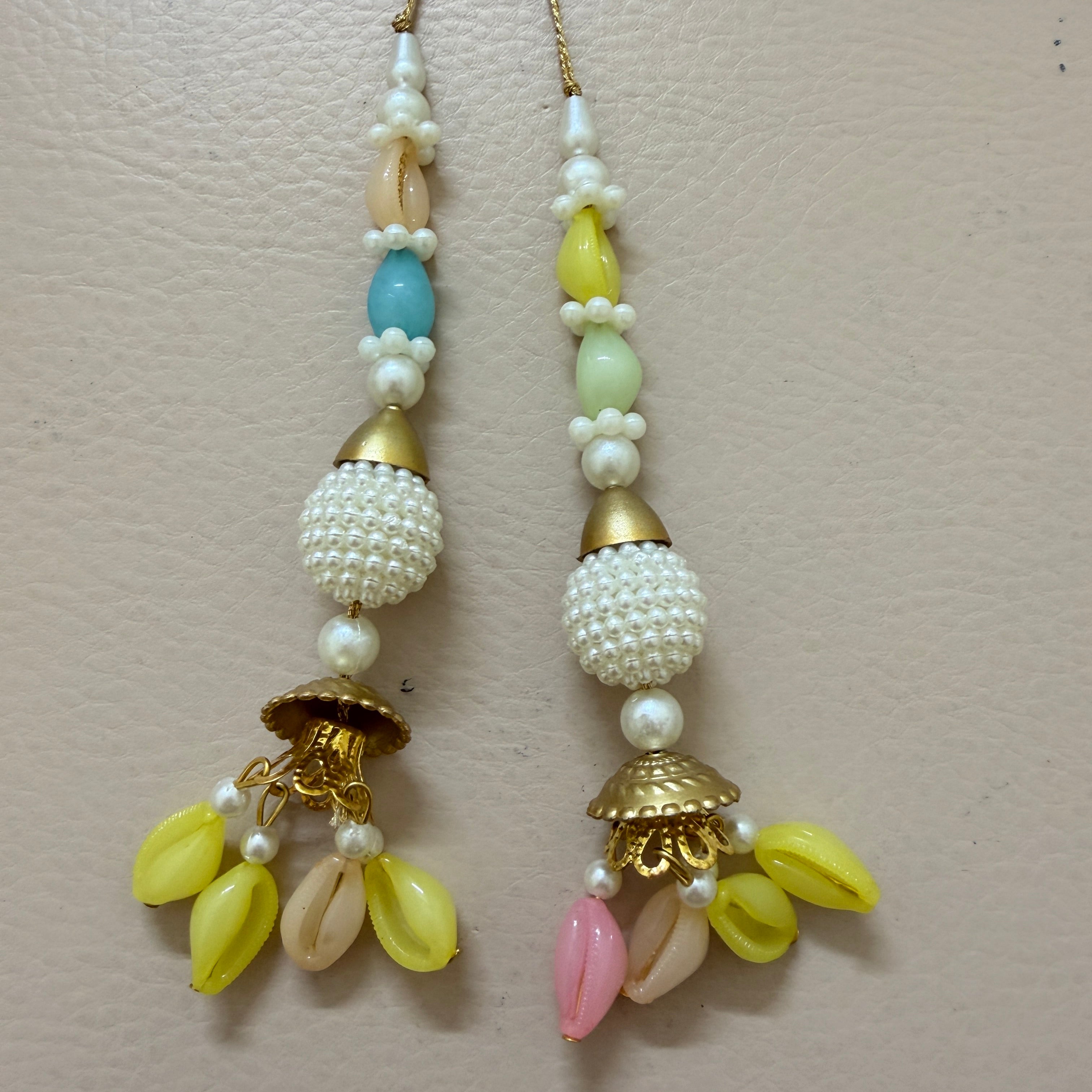 Pair of beaded earrings with gold accents on a light pink background