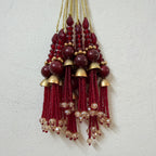 Decorative hanging with red beads and gold accents on a light gray background