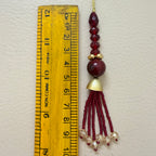 Decorative hanging ornament with beads and tassels next to a ruler for scale.