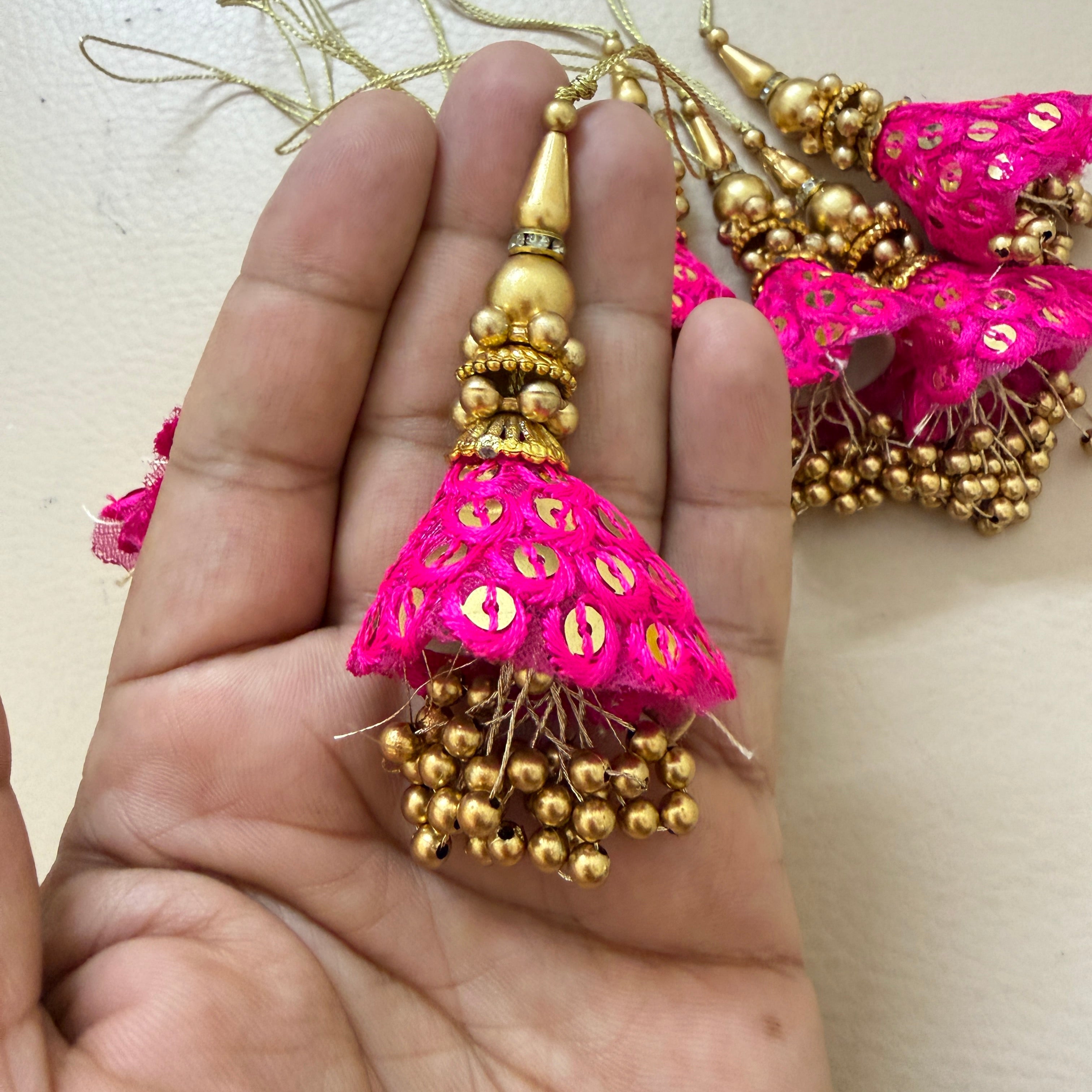 Pink and gold earrings held in a hand with a light background