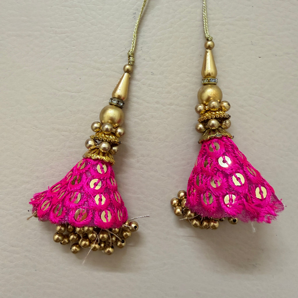Pair of pink tassel earrings with gold accents on a light gray background