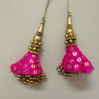 Pair of pink tassel earrings with gold accents on a light gray background