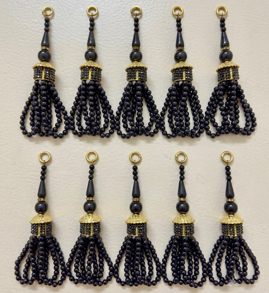 Set of black tassels with gold accents on a light gray background