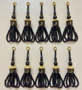 Set of black tassels with gold accents on a light gray background