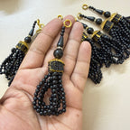 Set of black beaded tassels with gold accents on a light background