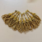 Gold beaded necklace on a light background