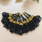 Black beaded necklace with gold accents on a beige surface