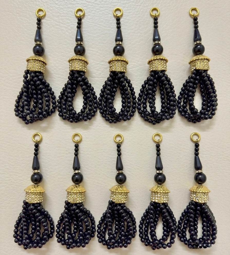 Set of black beaded tassels with gold accents on a beige background
