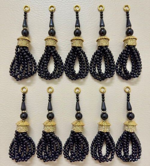 Set of black beaded tassels with gold accents on a beige background