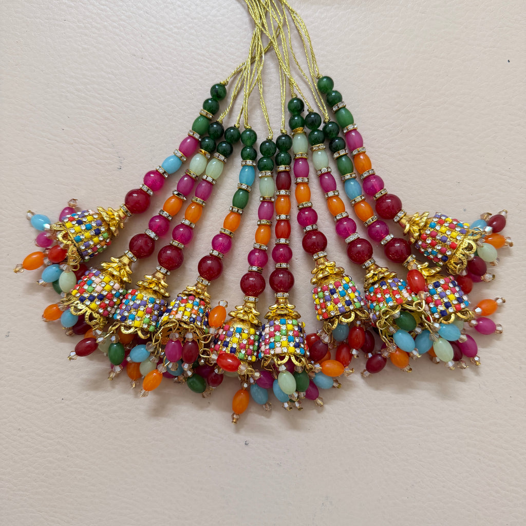 Colorful beaded jhumka earrings on a light pink background