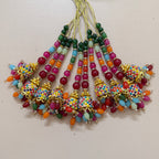 Colorful beaded jhumka earrings on a light pink background