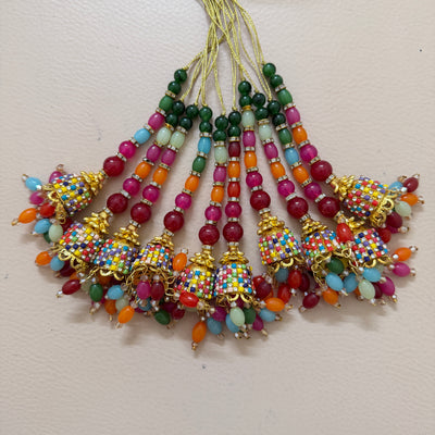 Colorful beaded jhumka earrings on a light pink background