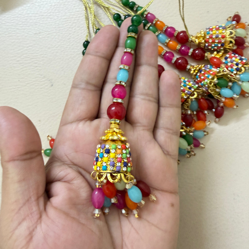 Colorful beaded tassel held in a hand against a neutral background