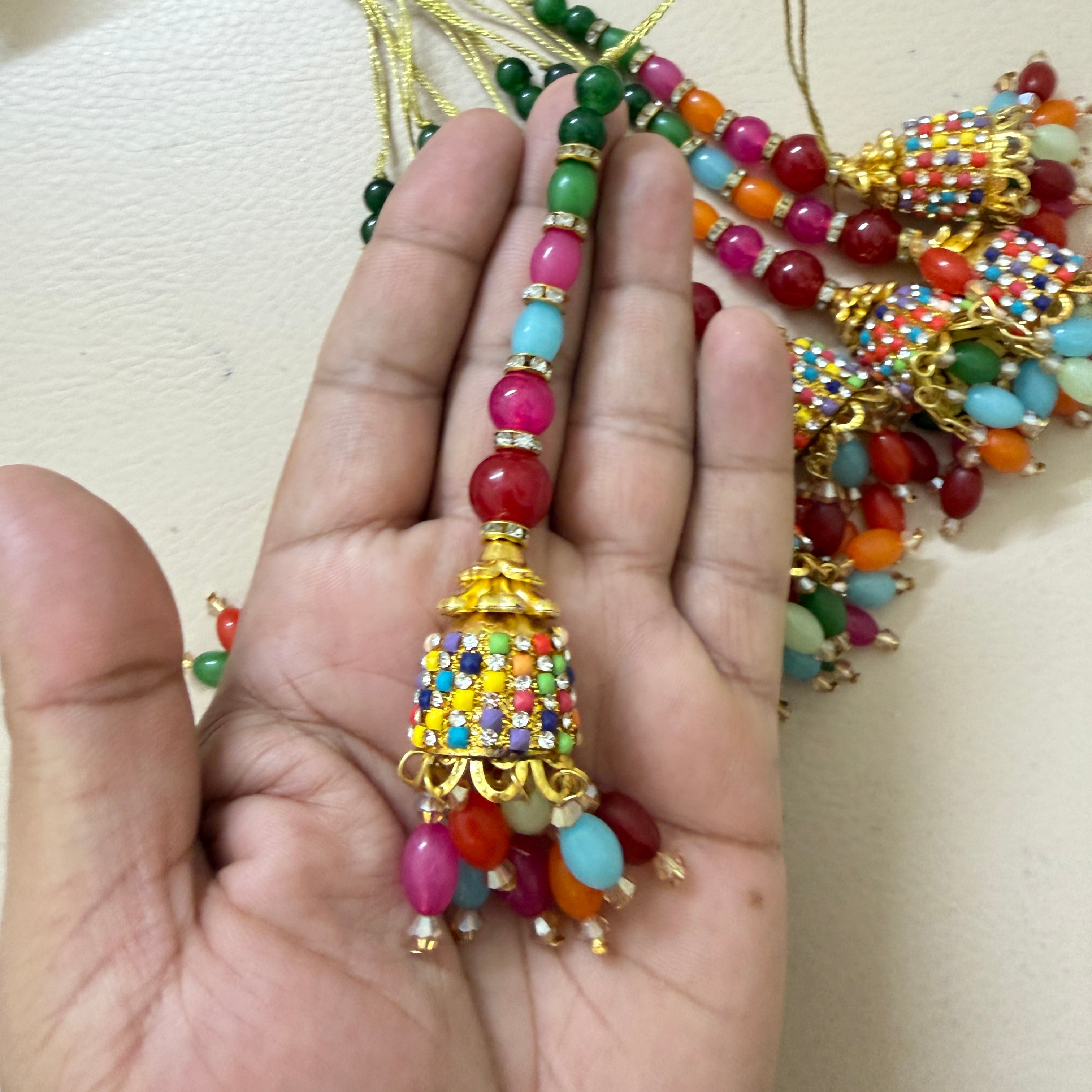 Colorful beaded tassel held in a hand against a neutral background