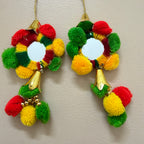 Pair of colorful pom-pom earrings with gold accents on a beige background